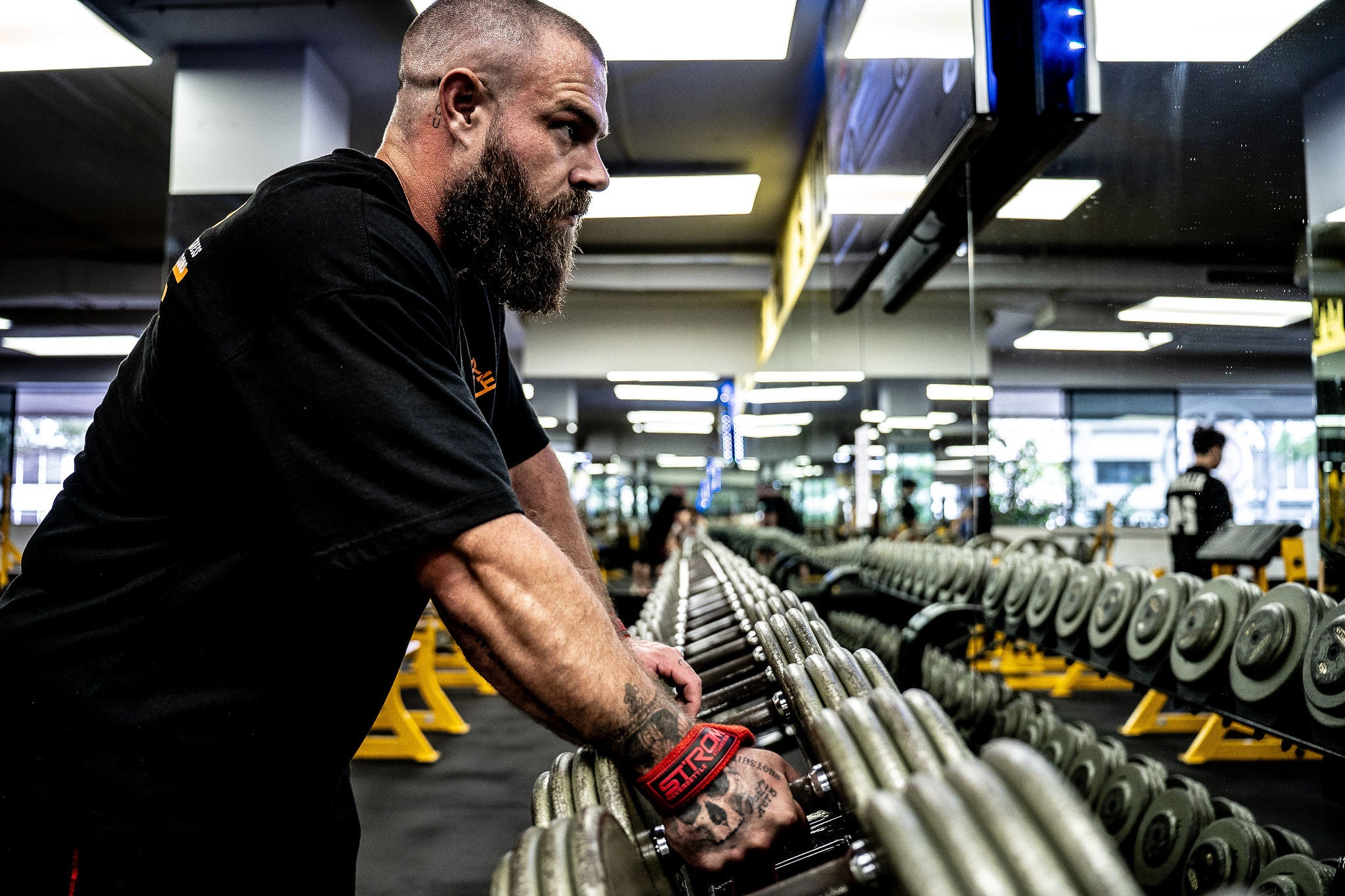 Man lifting weights in a gym setting wearing a STrom Au NEVER Settle Tee | Trusted by Australian athletes – Shop now at Strom Sports Australia.