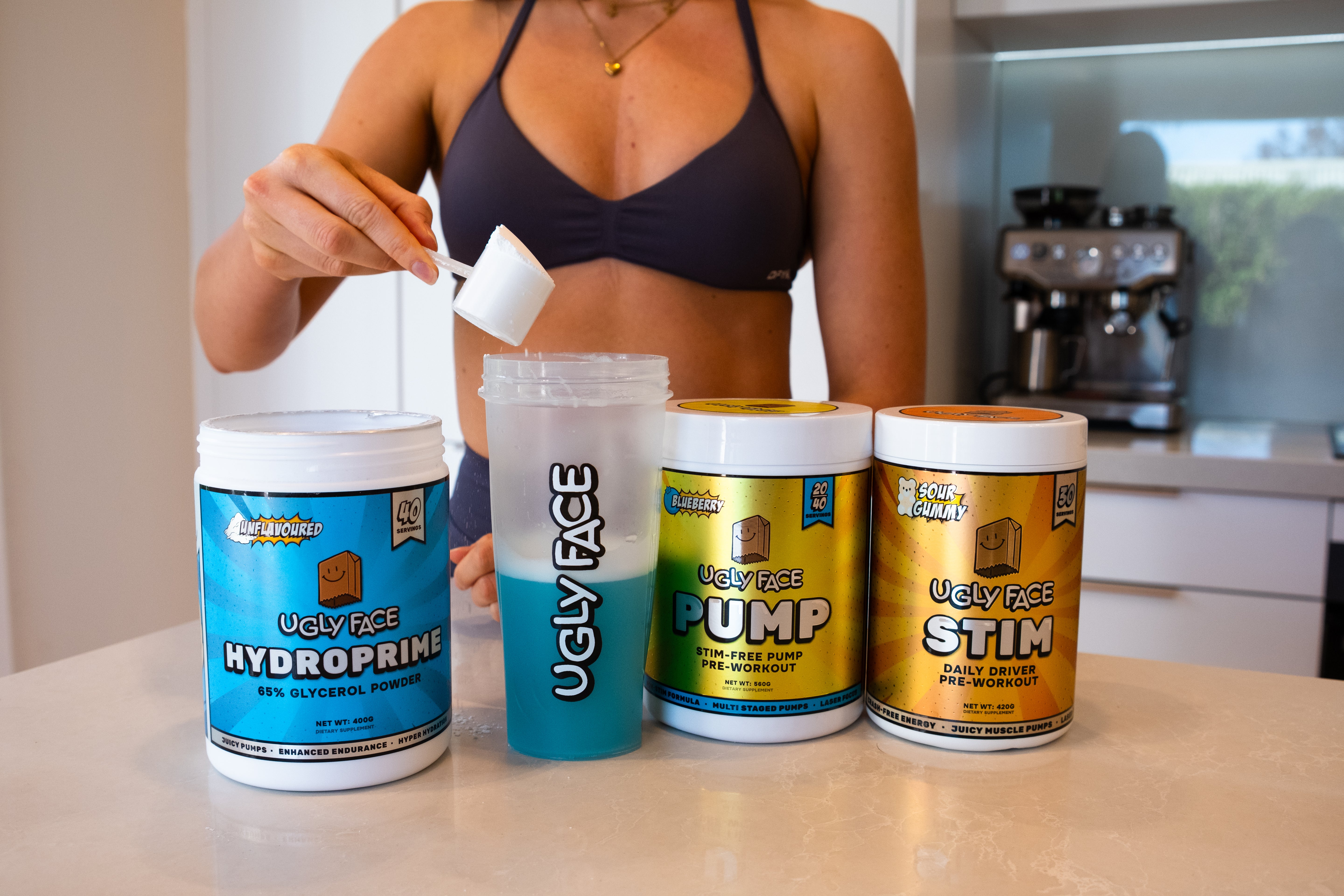 Person holding a supplement container with Ugly Face Preworkout products on a kitchen counter.Strom Sports Supplements Australia
